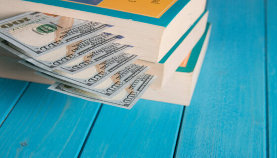 an image of a stack of books and money, symbolising the connection between writing and financial gain.