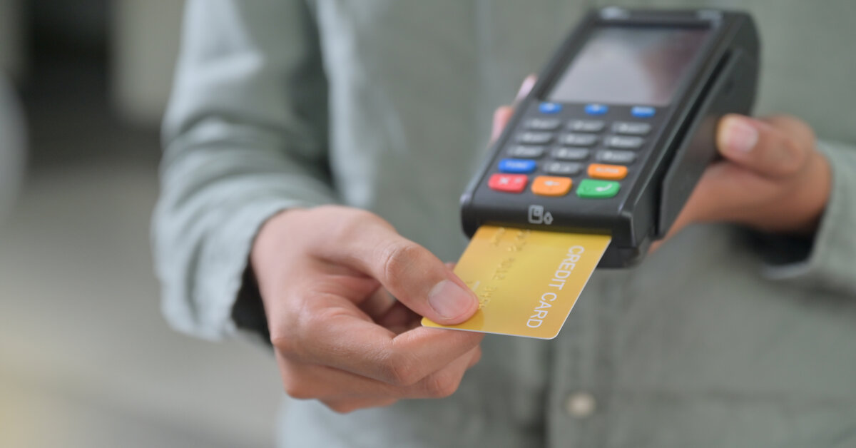 A person holding a credit card with a credit card machine, symbolising the idea of accepting credit card payments.