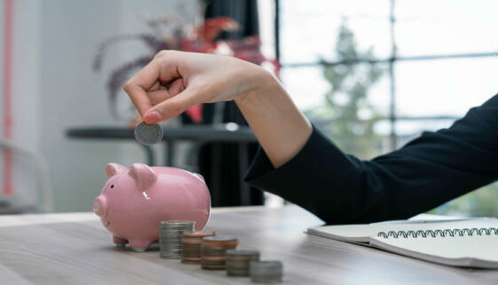 A woman puts coins in a piggy bank to save money and plan for it after retirement.