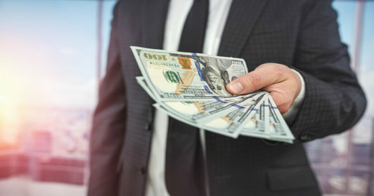 a person holding a stack of money, symbolizing the goal of getting funding for a startup.