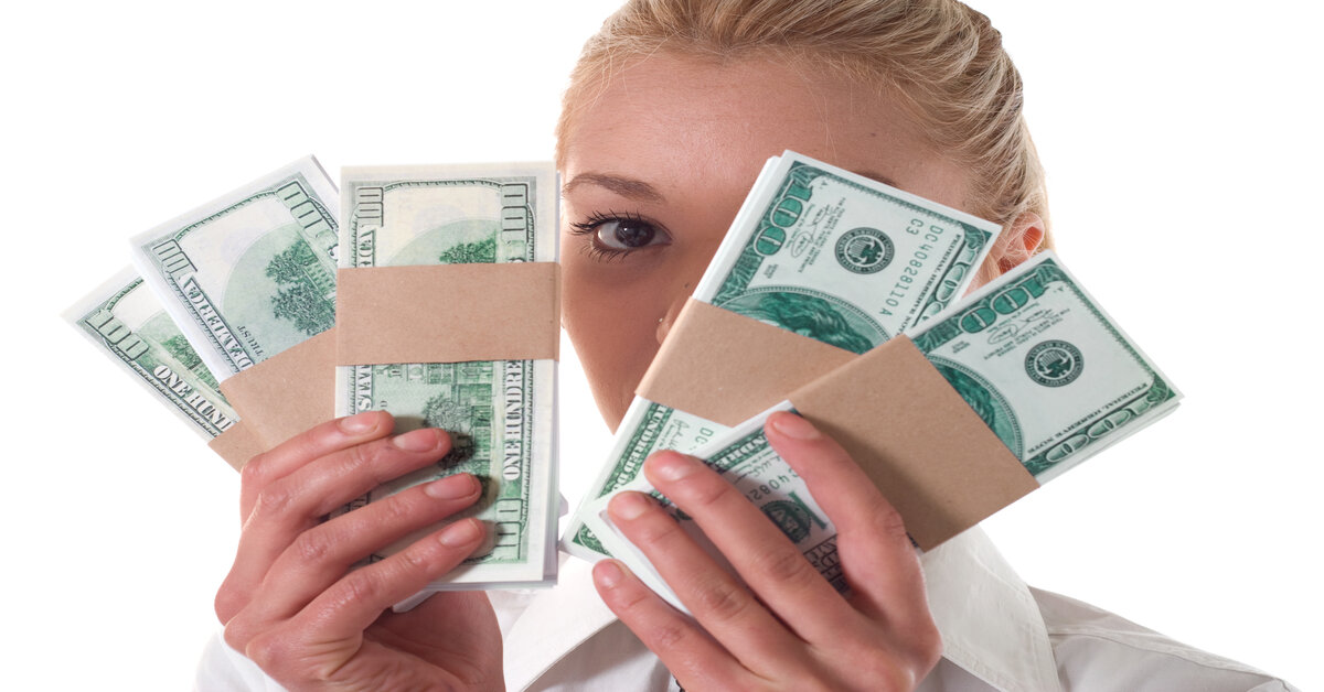 A young woman holds a wad of cash. 