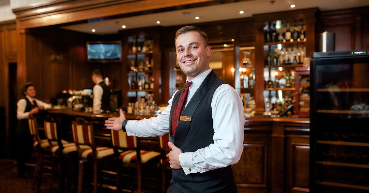 A portrait of a smiling waiter welcoming guests, emphasizing the importance of hospitality in creating positive and memorable experiences.
