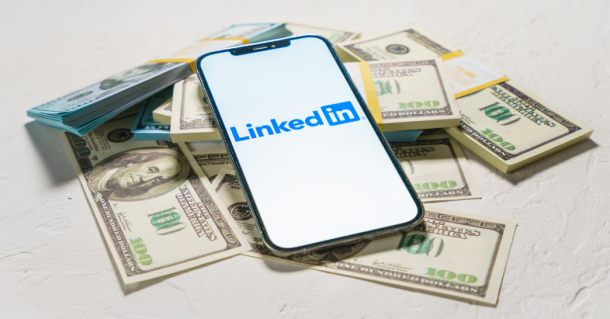 A mobile phone placed above US bank notes symbolizing money made using LinkedIn