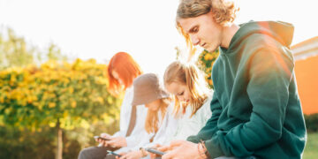 A bunch of different aged people sitting outside and spending time using social media