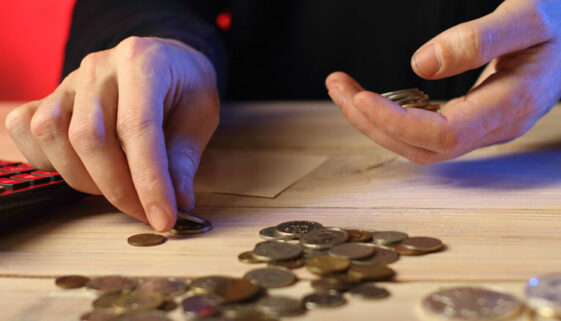 A person counting coins symbolises the idea of being mindful of every penny spent and sticking to a budget.