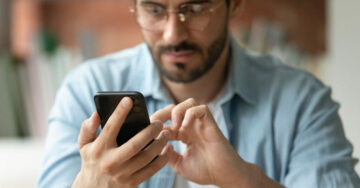 A person holding a smartphone and scrolling through social media, symbolising the impact of widespread social media use in modern society. 