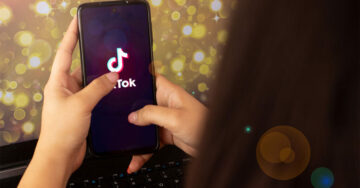 A person is holding a smartphone, with a TikTok ad playing on the screen.