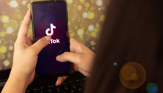 A person is holding a smartphone, with a TikTok ad playing on the screen.