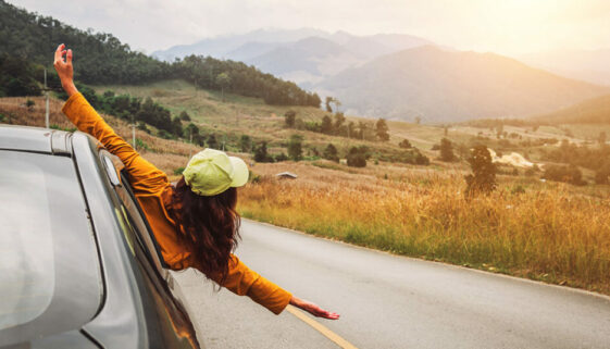 An independent women happy and celebrating out of a car window