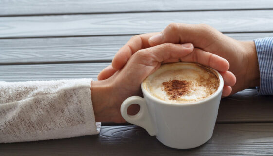 Man and women hold hands with a coffee cup shows how to build trust and strengthen relationship