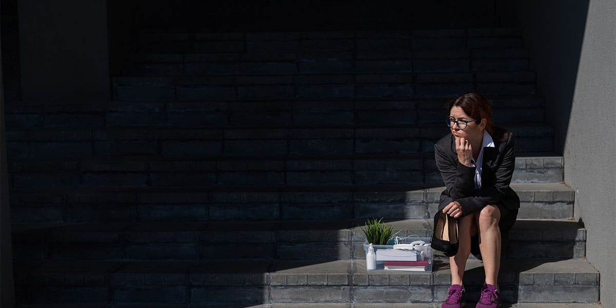 Depressed woman sitting beneath a property thinking about buying property without money.