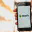 A hand with a phone showing how Shopify used for